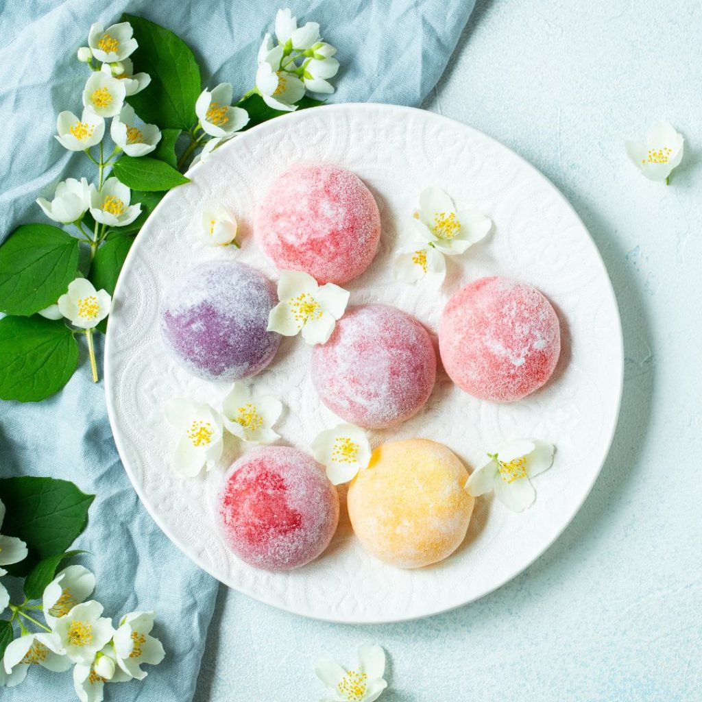 A plate of Japanese desserts lies on a table with flowers.