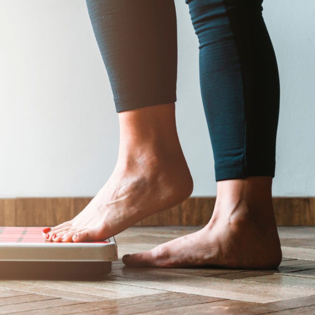 A woman steps on a weighing scale.