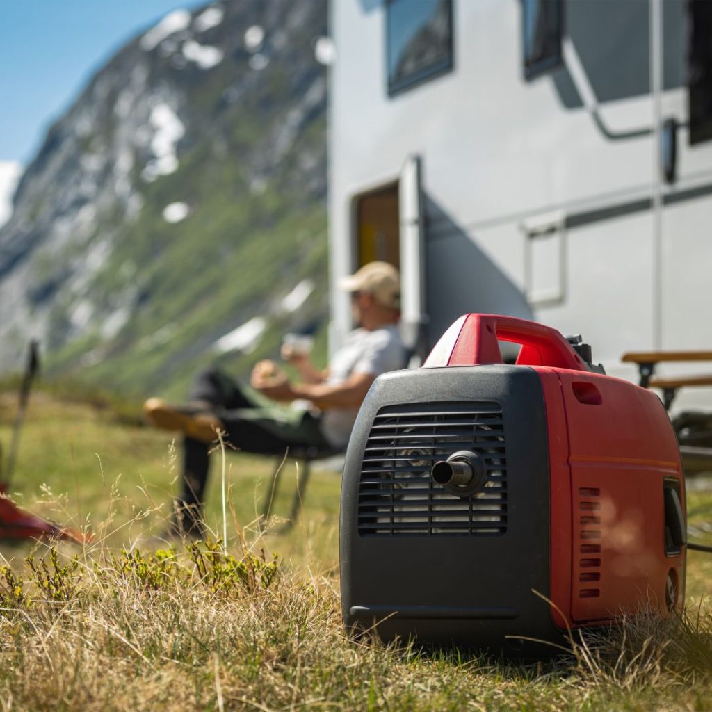 A portable generator sits in the grass next to an RV.