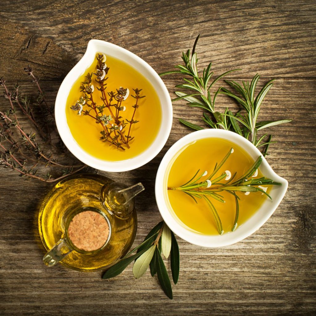 Different types of olive oil rest on a wooden table.