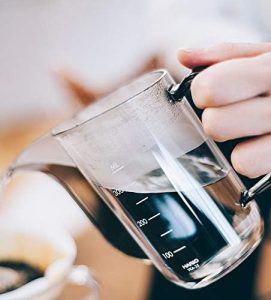 A person pouring coffee into a Hario Air Kettle.