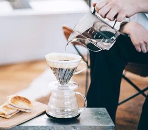 A person pouring coffee into a Hario Air Kettle for review.