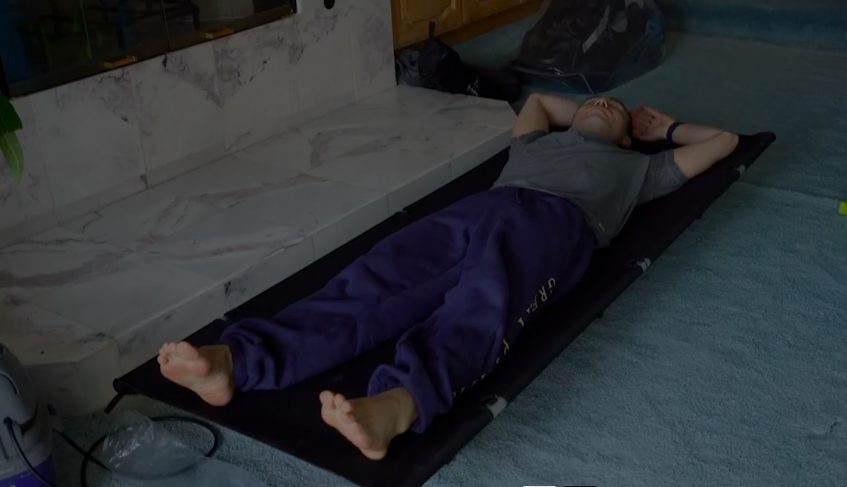 Pat Tokuyama resting on a Helinox Cot Max in a room.