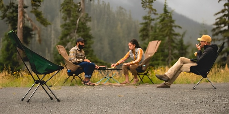 A group of people enjoying a Helinox Sunset Chair around a campfire.