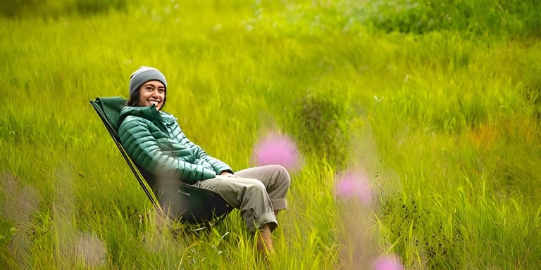 A man testing the Helinox Sunset Chair in a picturesque grassy field.