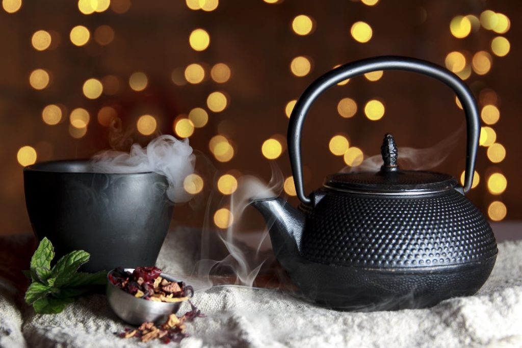 A cast iron Japanese teapot next to a cup of tea on a table.