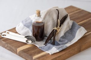 A cutting board with a bottle of Native Vanilla syrup and measuring spoons.