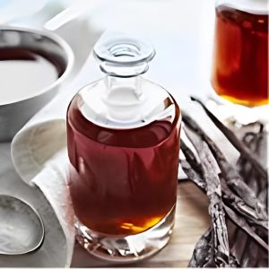 A bottle of vanilla syrup on a table next to a spoon.