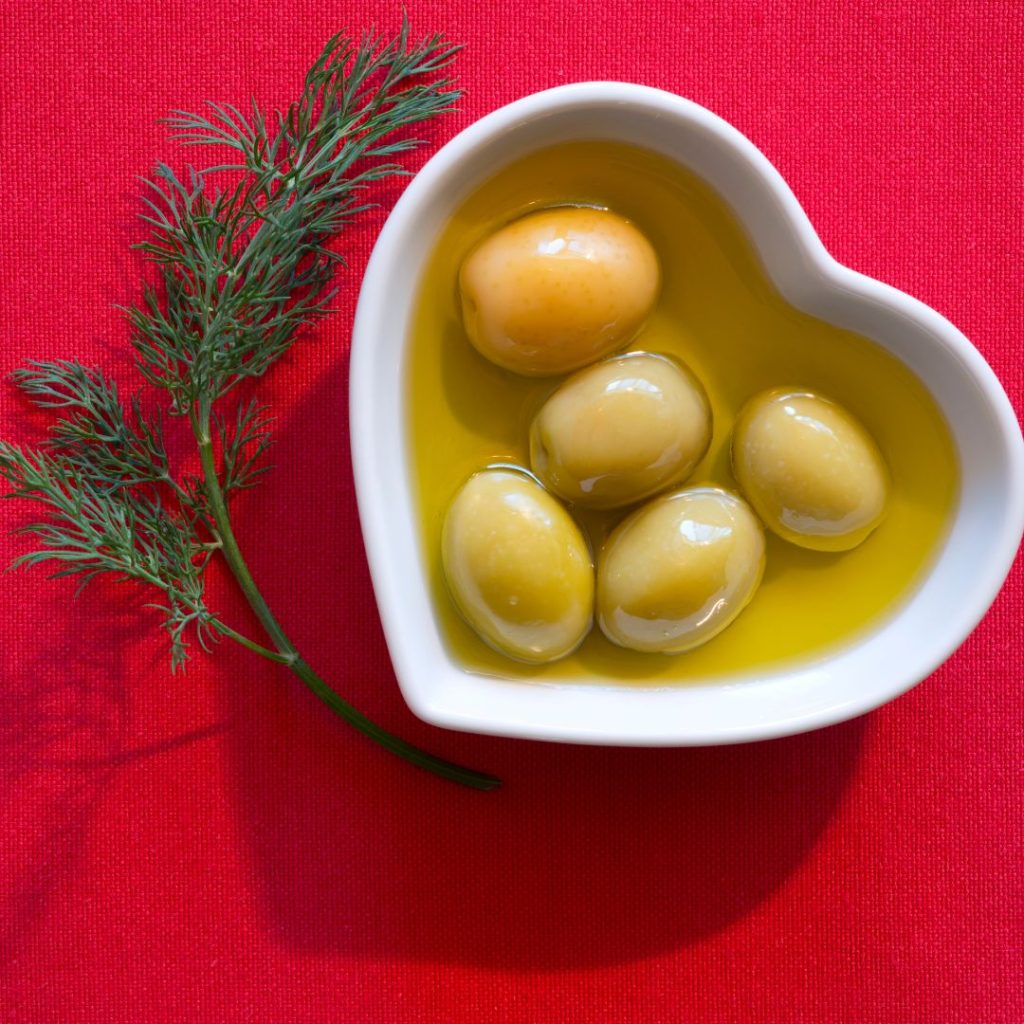 Olives and olive oil rest serenely within a heart-shaped container.