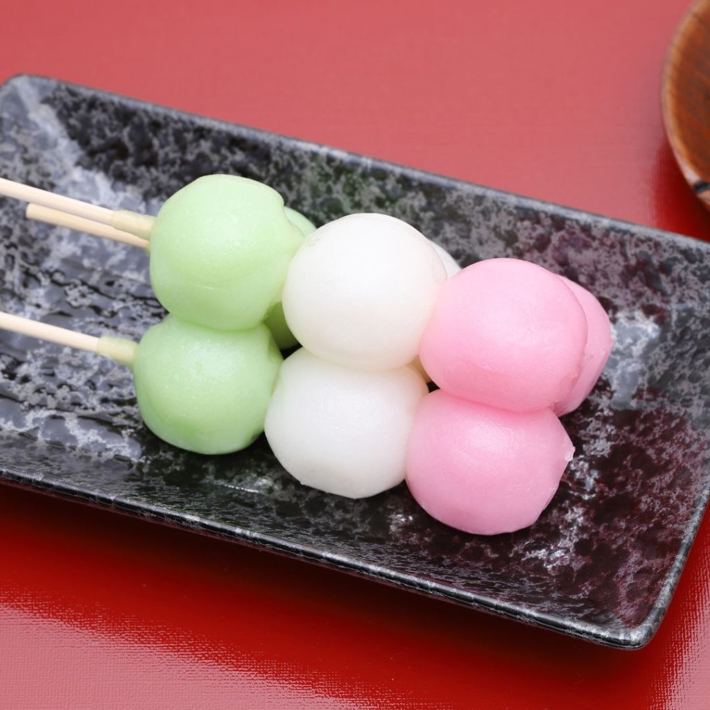 Skewered Japanese desserts rest on a marble plate.