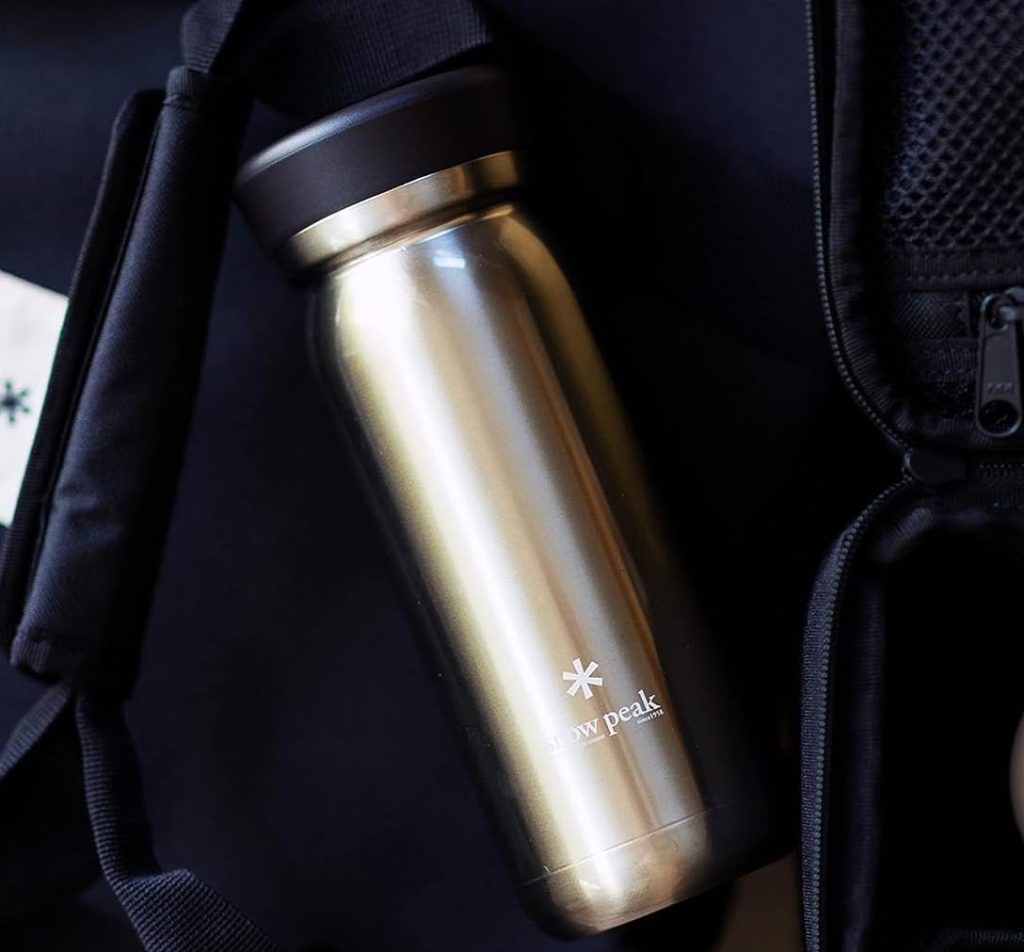 A stainless steel water bottle next to a Snow Peak backpack.