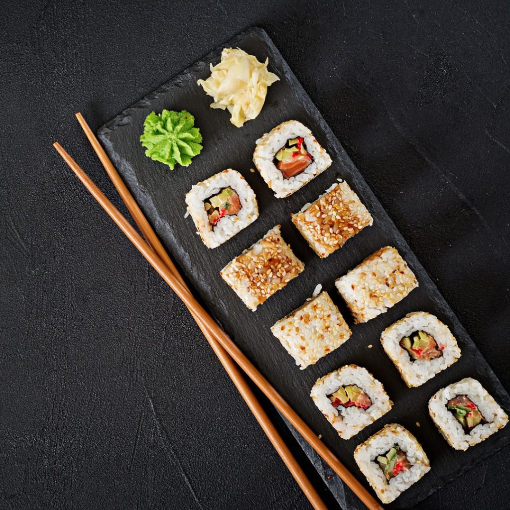 Sushi rolls lie on a table with a pair of chopsticks.