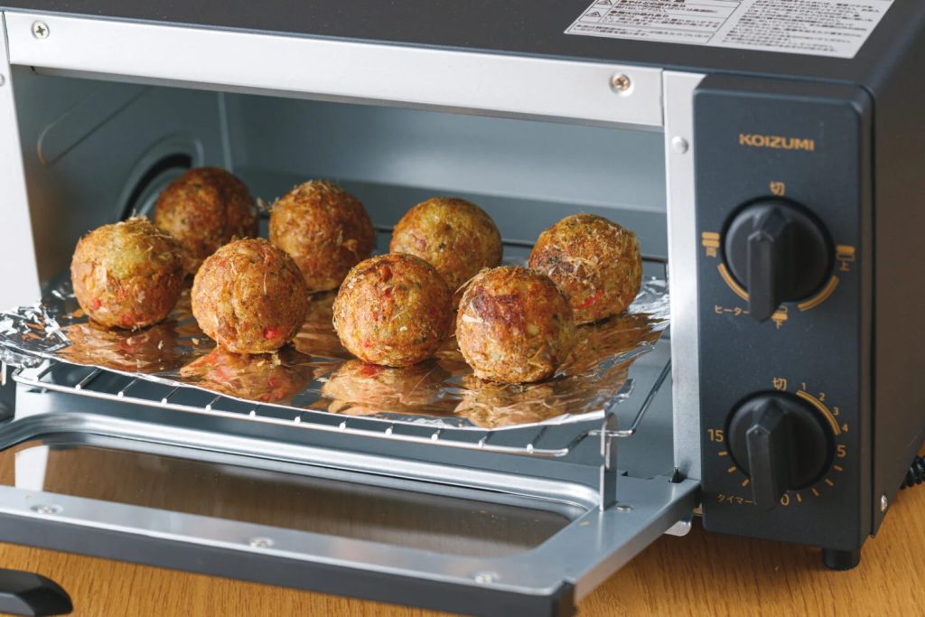 A toaster oven with several takoyaki in it.