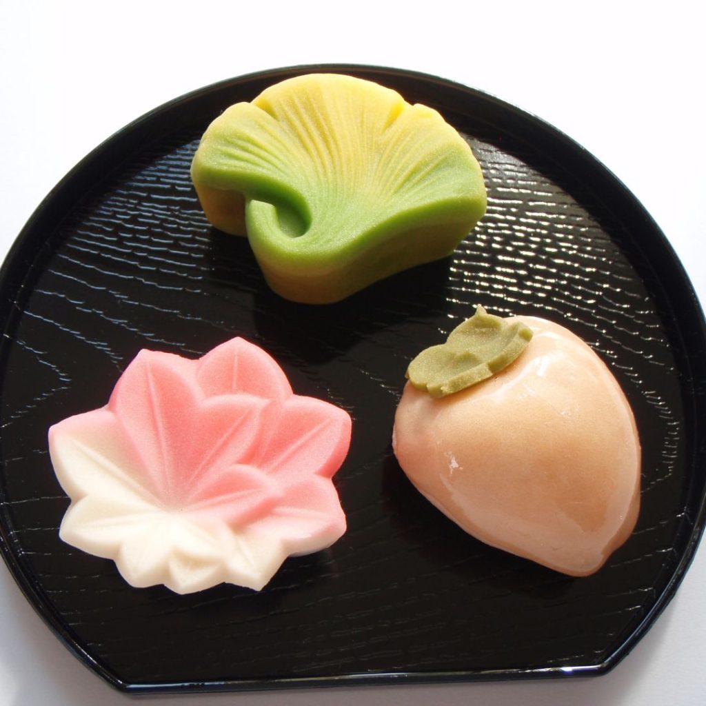 Three different Japanese desserts rest on a black plate.