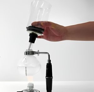 A person is brewing coffee using a Hario Syphon.