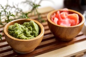 Two wooden bowls filled with different types of sauce including wasabi.