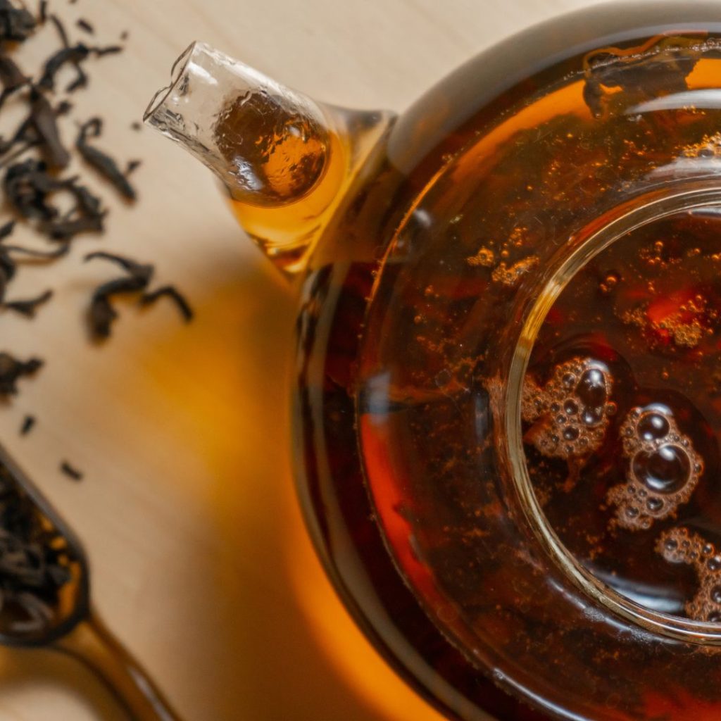 A Maru Teapot filled with black tea and a spoon.