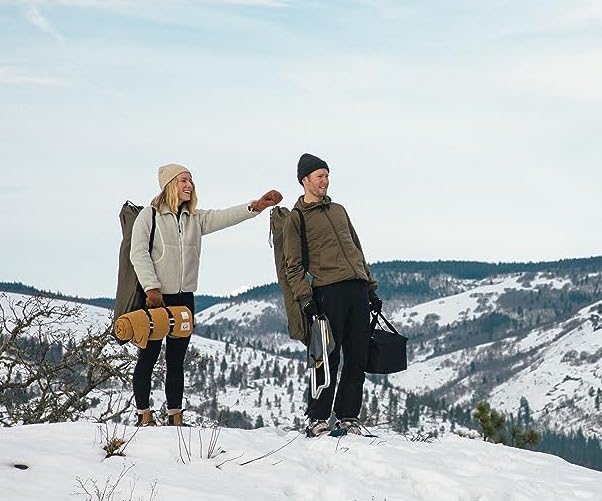 Two people standing on top of a snowy mountain with a milk bottle.