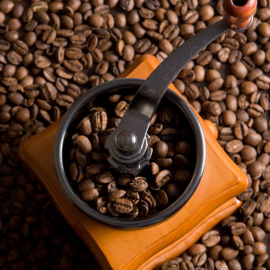 A coffee grinder resting on top of coffee beans.