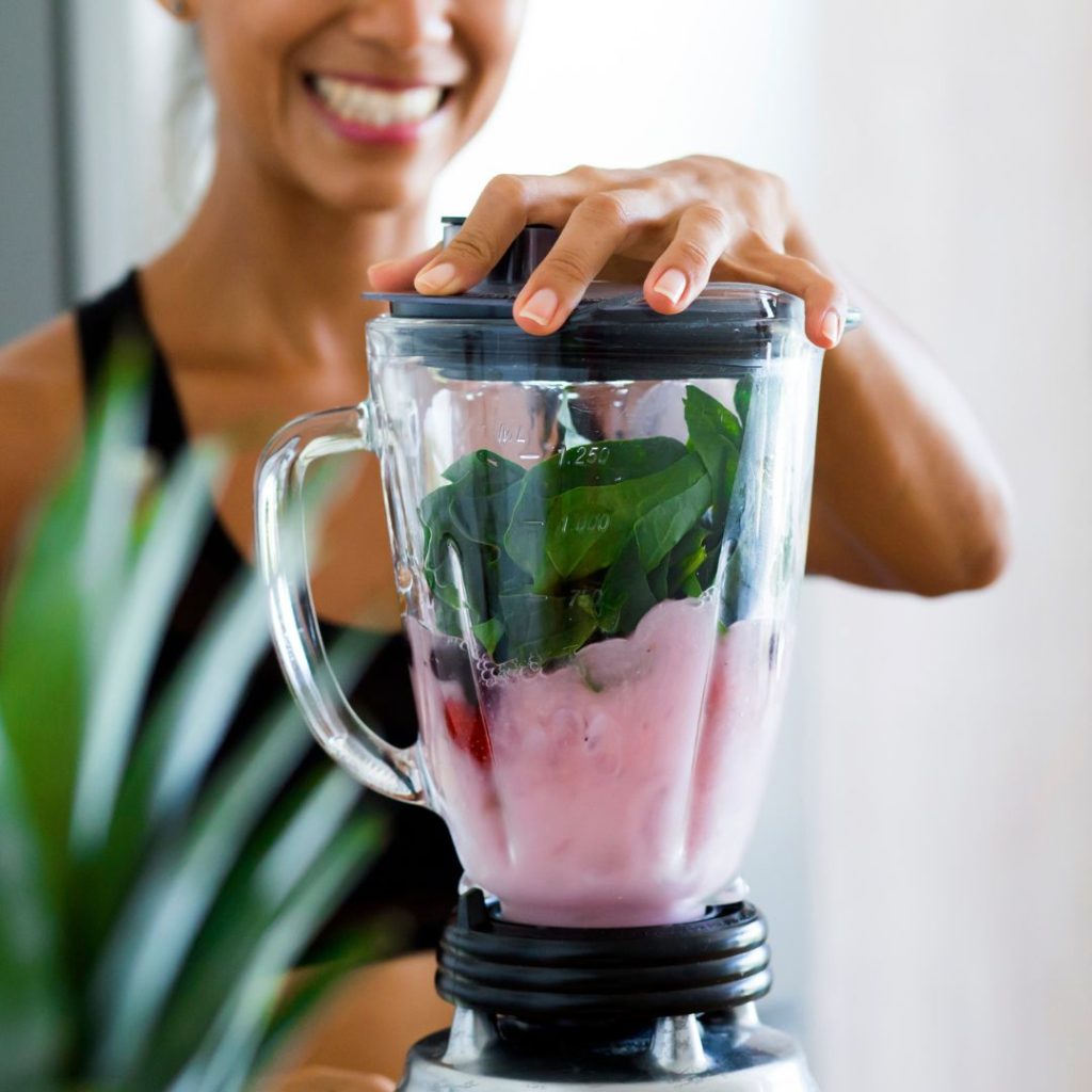 A woman is blending a smoothie in a Vitamix blender.