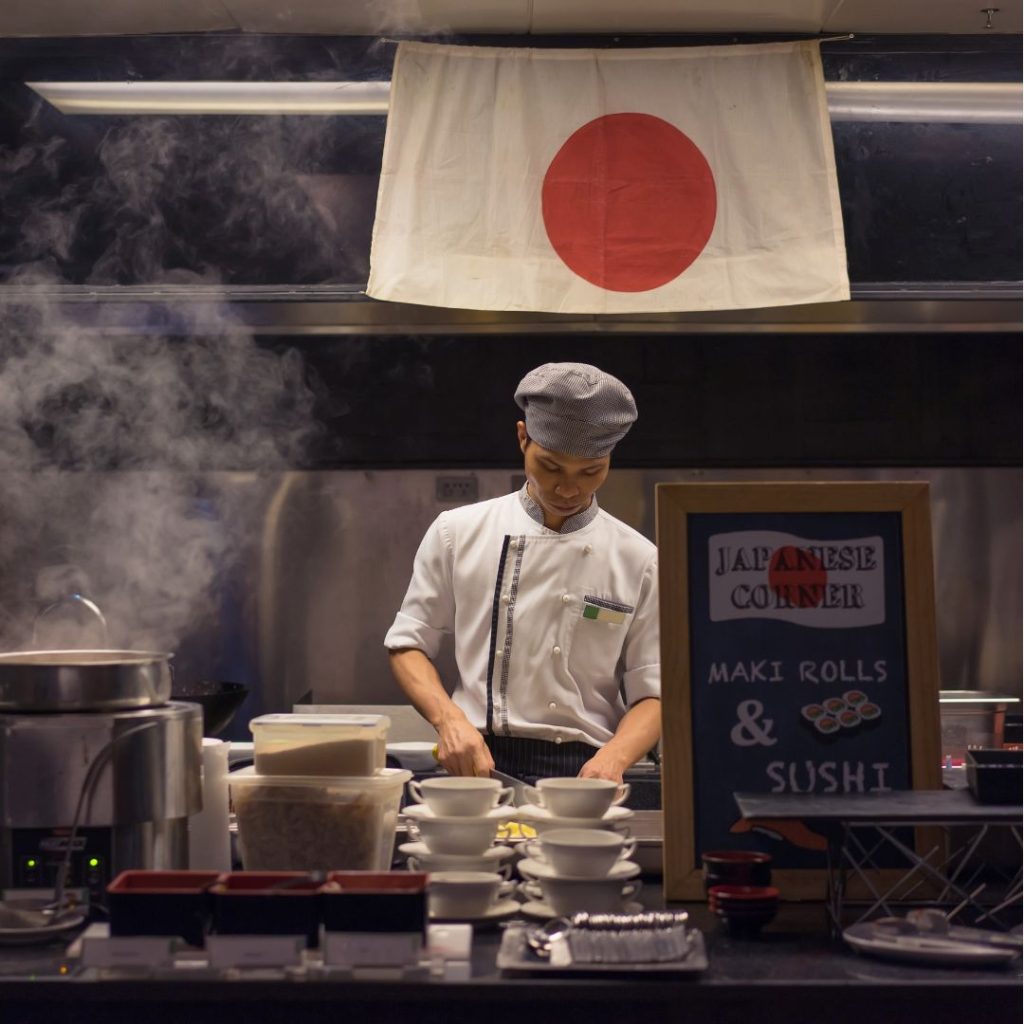 A man is preparing Japanese dishes in a kitchen.