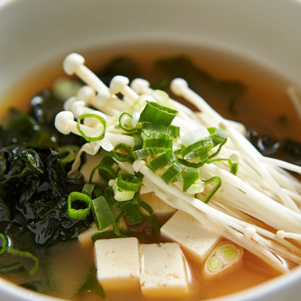 A miso soup with tofu and green onions.