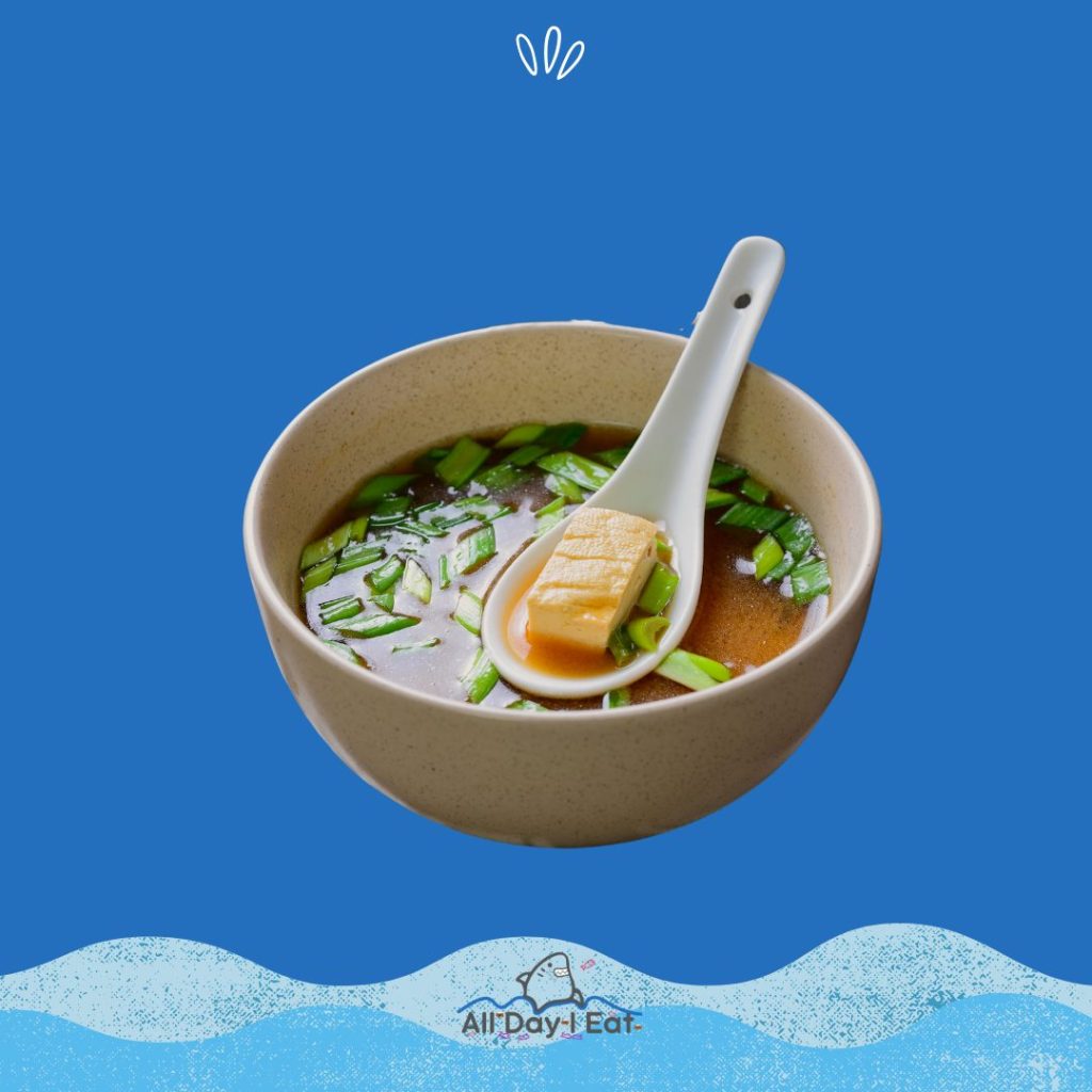 A bowl of miso soup on a blue background.