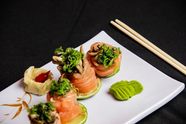 A plate with sushi and chopsticks, wasabi.