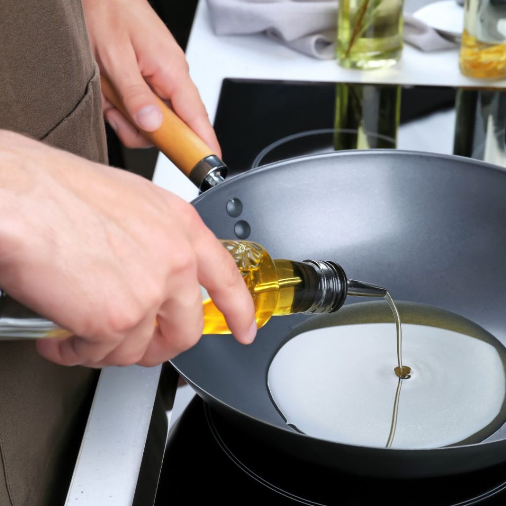 Extra virgin olive oil gets poured on a wok.