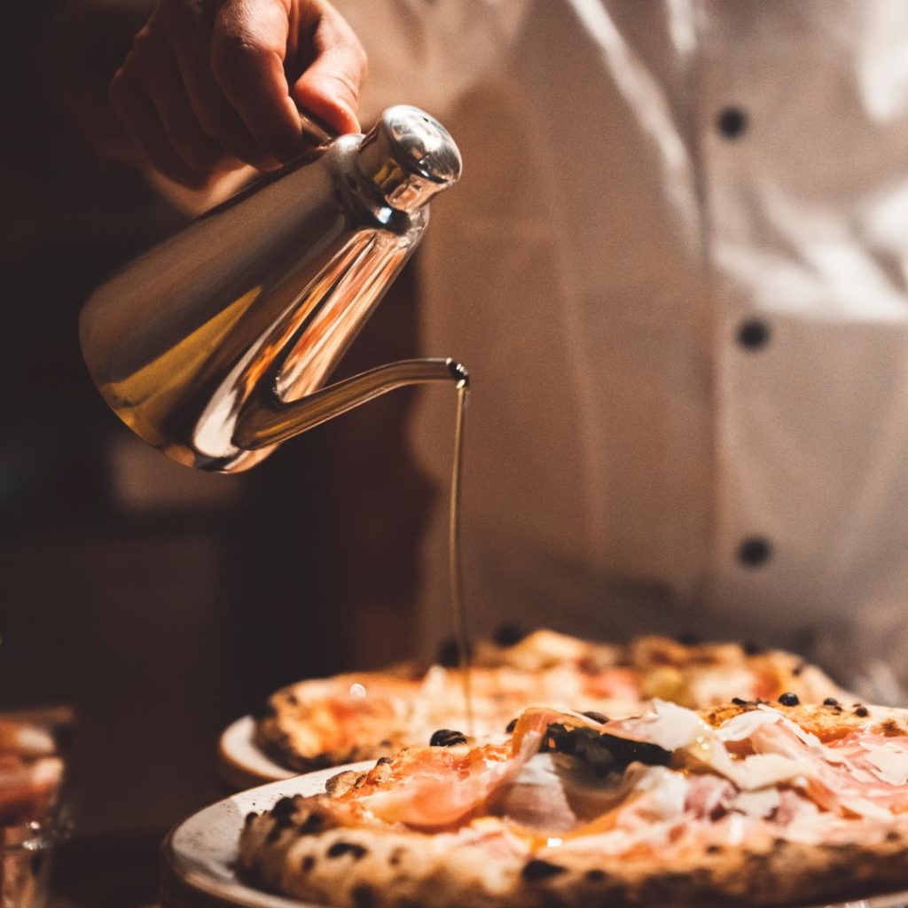 A chef drizzles extra virgin olive oil into a pastry after baking.