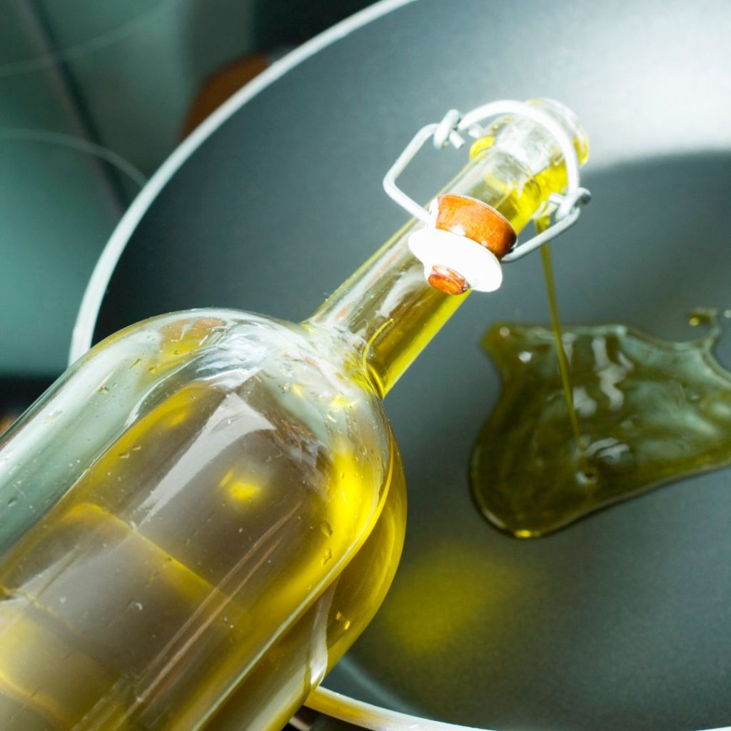 Extra virgin olive oil gets poured into a pan.