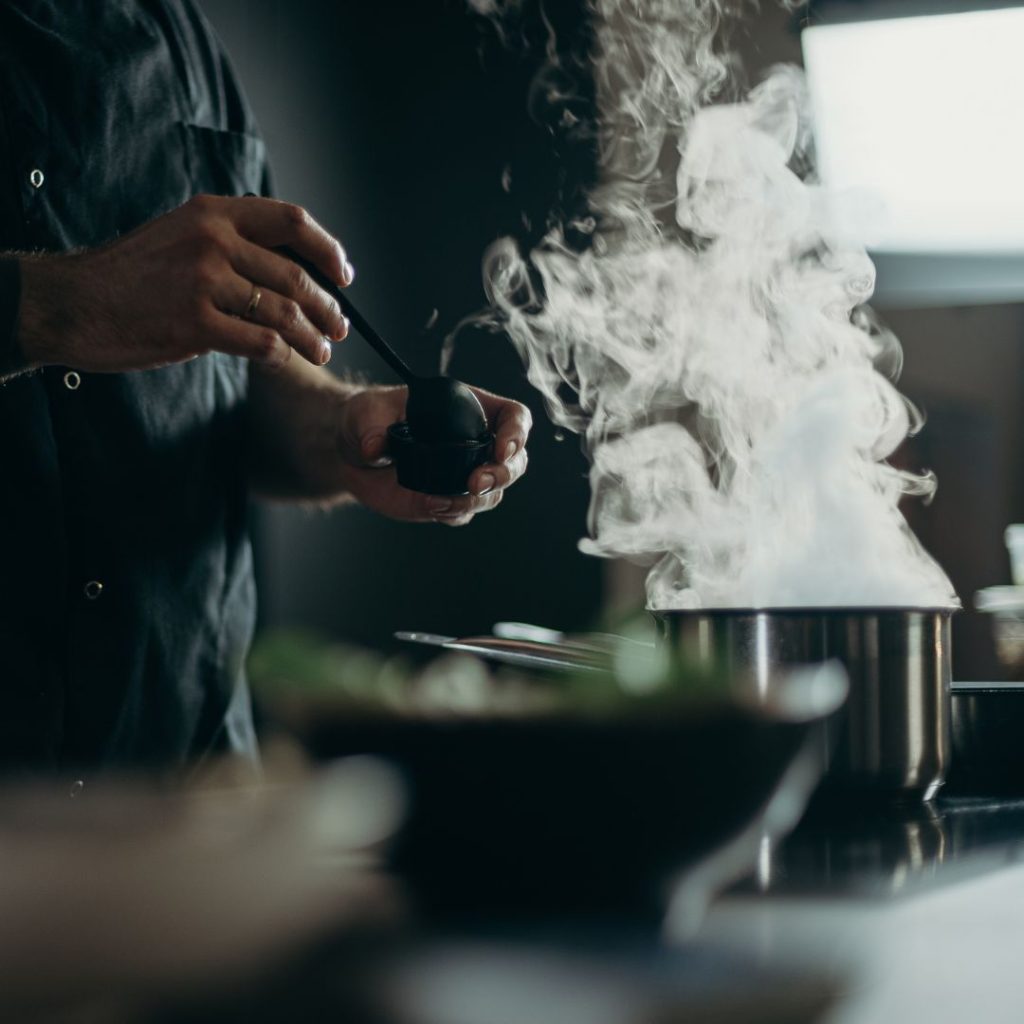 A cooking pan produces intense smoke as the chef increases the stove's heat.