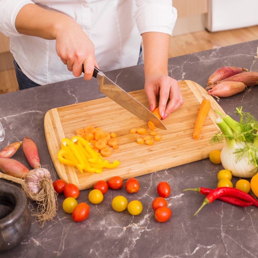 A chef cuts a carrot with a knife.