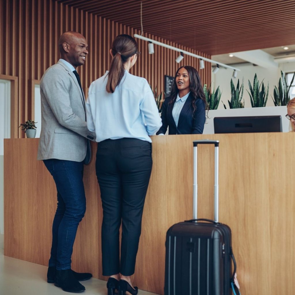 A couple stands before the hotel reception as they book their room.