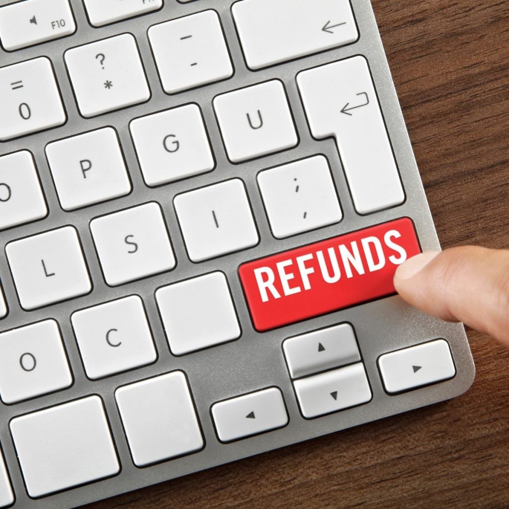 A human finger hits a "refunds" button on a keyboard.