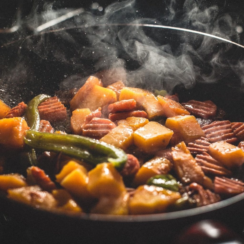 A variety of foods are being cooked on a cooking pan.