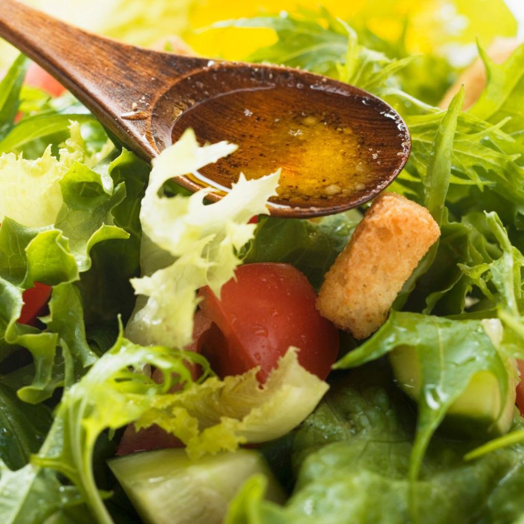 Extra virgin olive oil gets drizzled over a spoon before putting it on the salads.