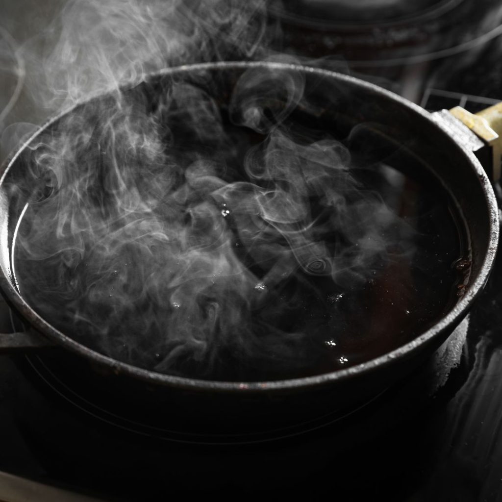 Oil smokes up as it rests on a pan in high heat.