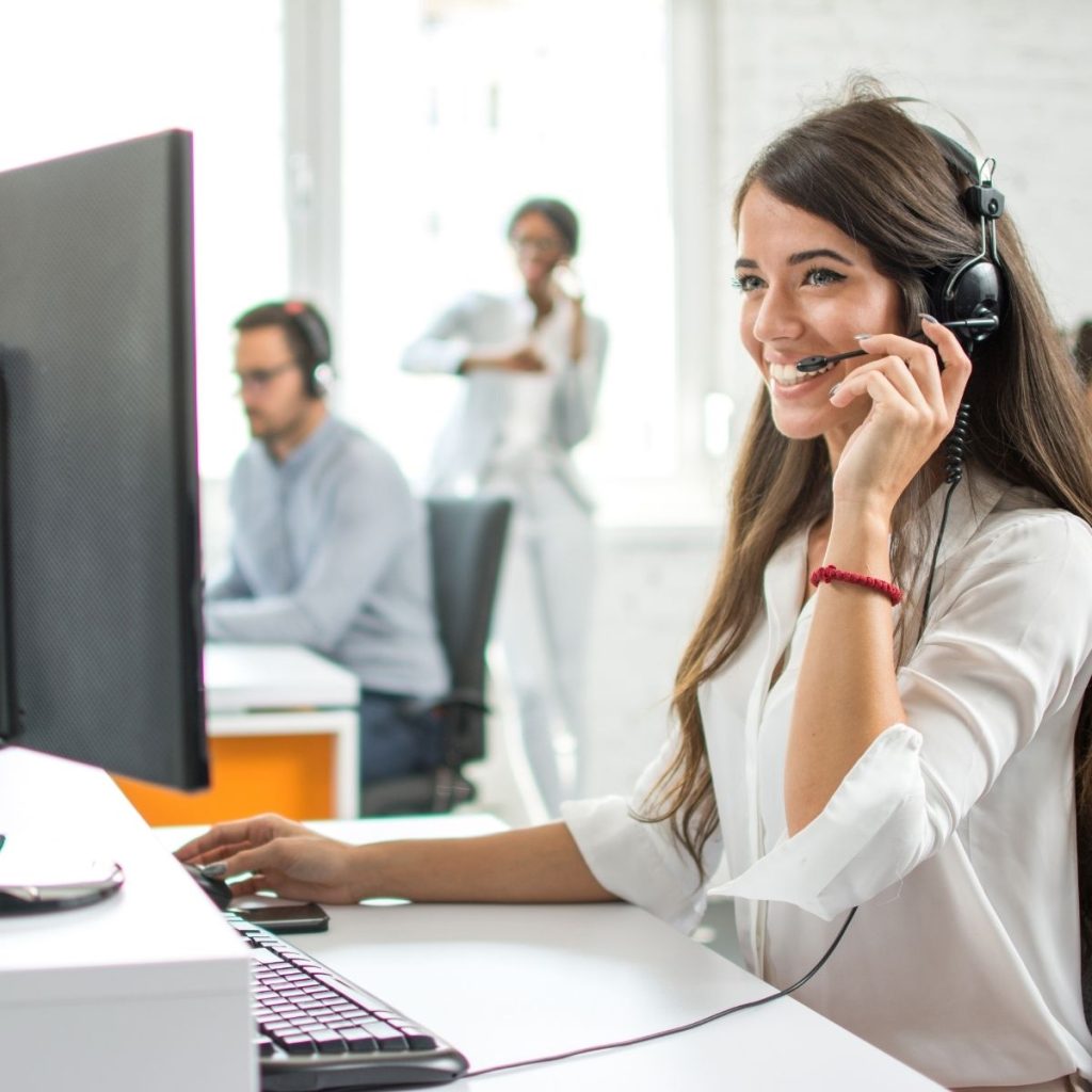 A customer service representative smiles while taking a call.