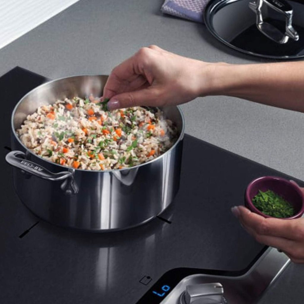 A human sprinkles parsley over some vegetables cooking in an All-Clad Weeknight Pan. (Photo courtesy of Amazon)