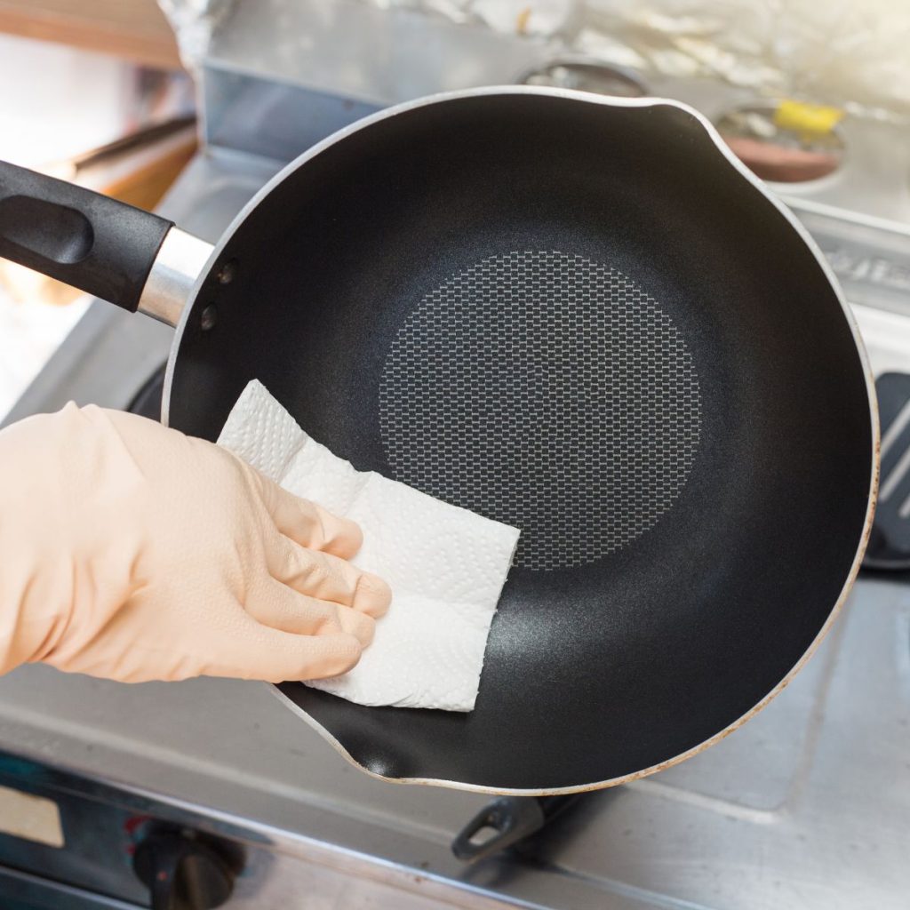 A newly washed steel pan is dried with a paper towel.