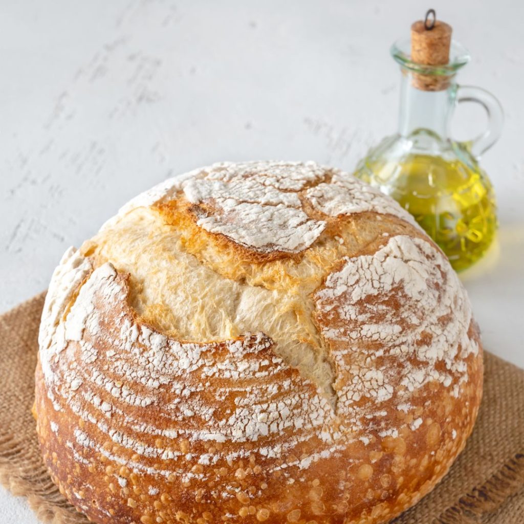 A pastry sits on a tablecloth with a bottle of extra virgin olive oil.