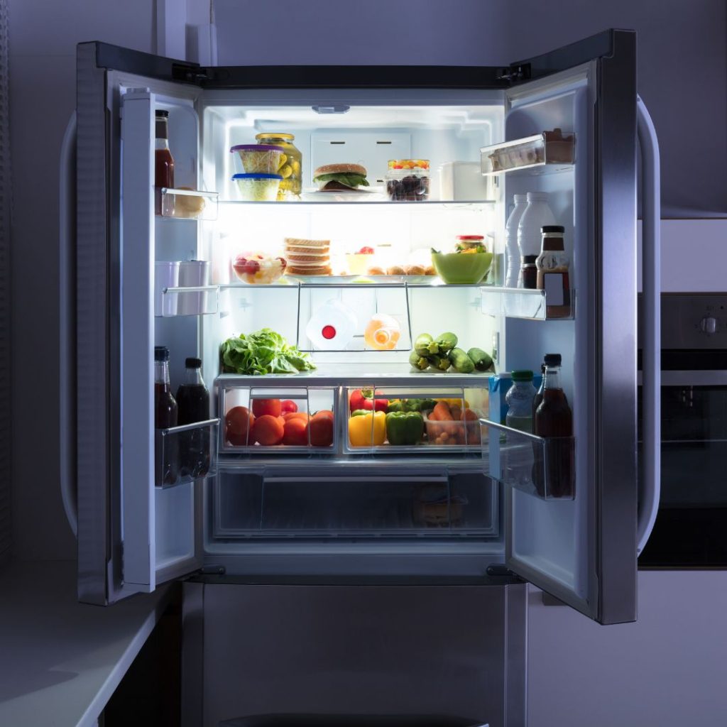 A refrigerator is wide open and shows all its contents.