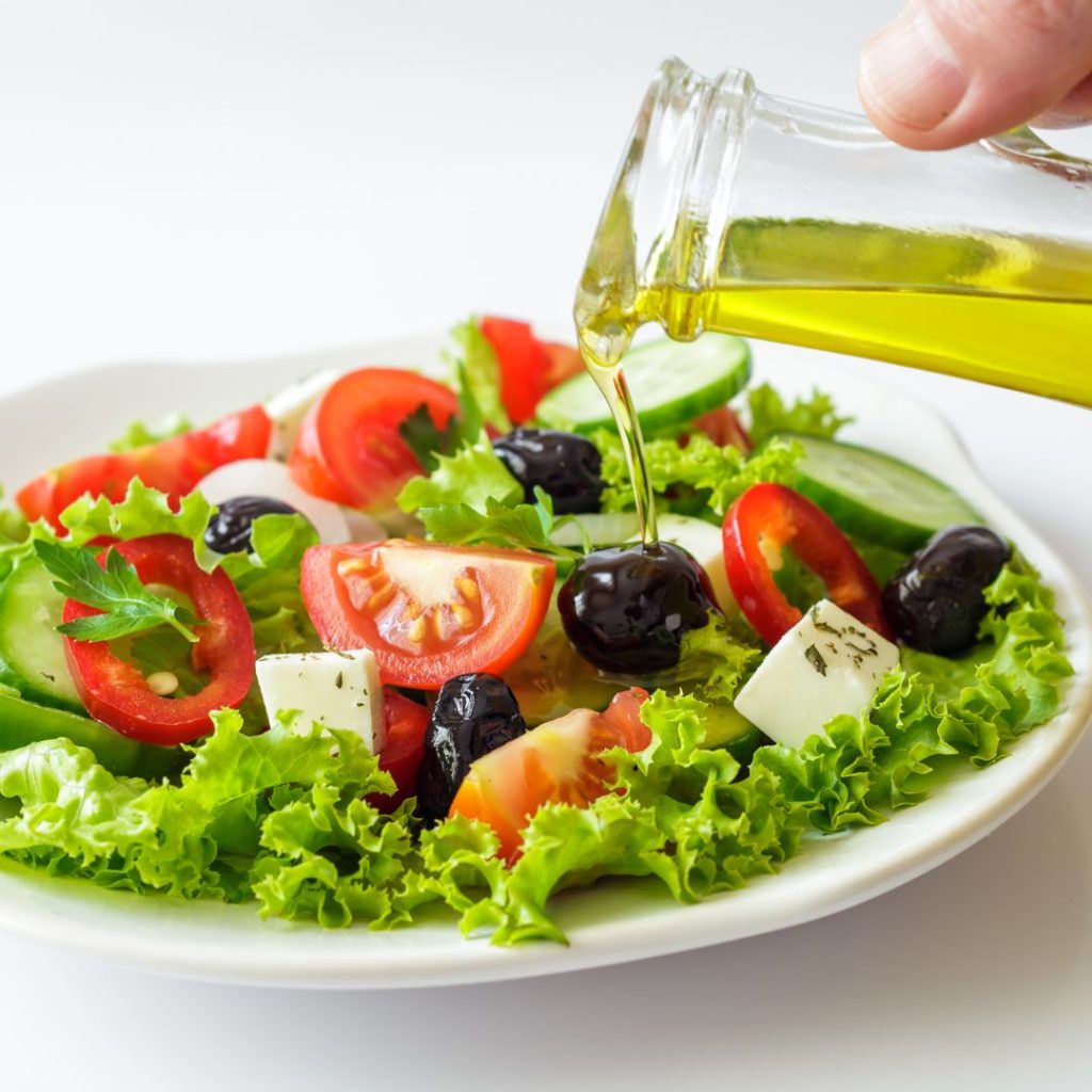 Extra virgin olive oil gets poured on a salad plate.