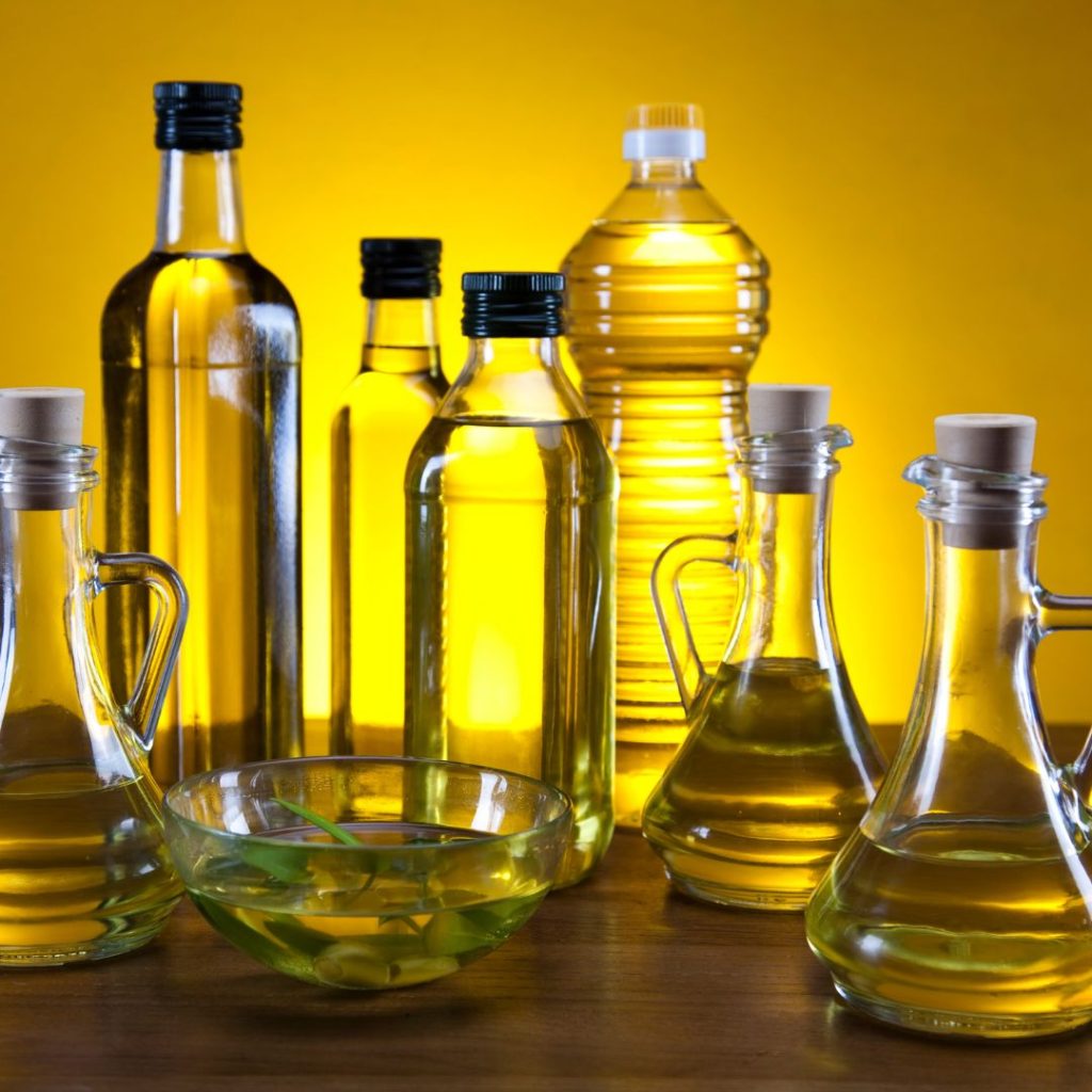 Multiple bottles of extra virgin olive oil rest on a wooden table.