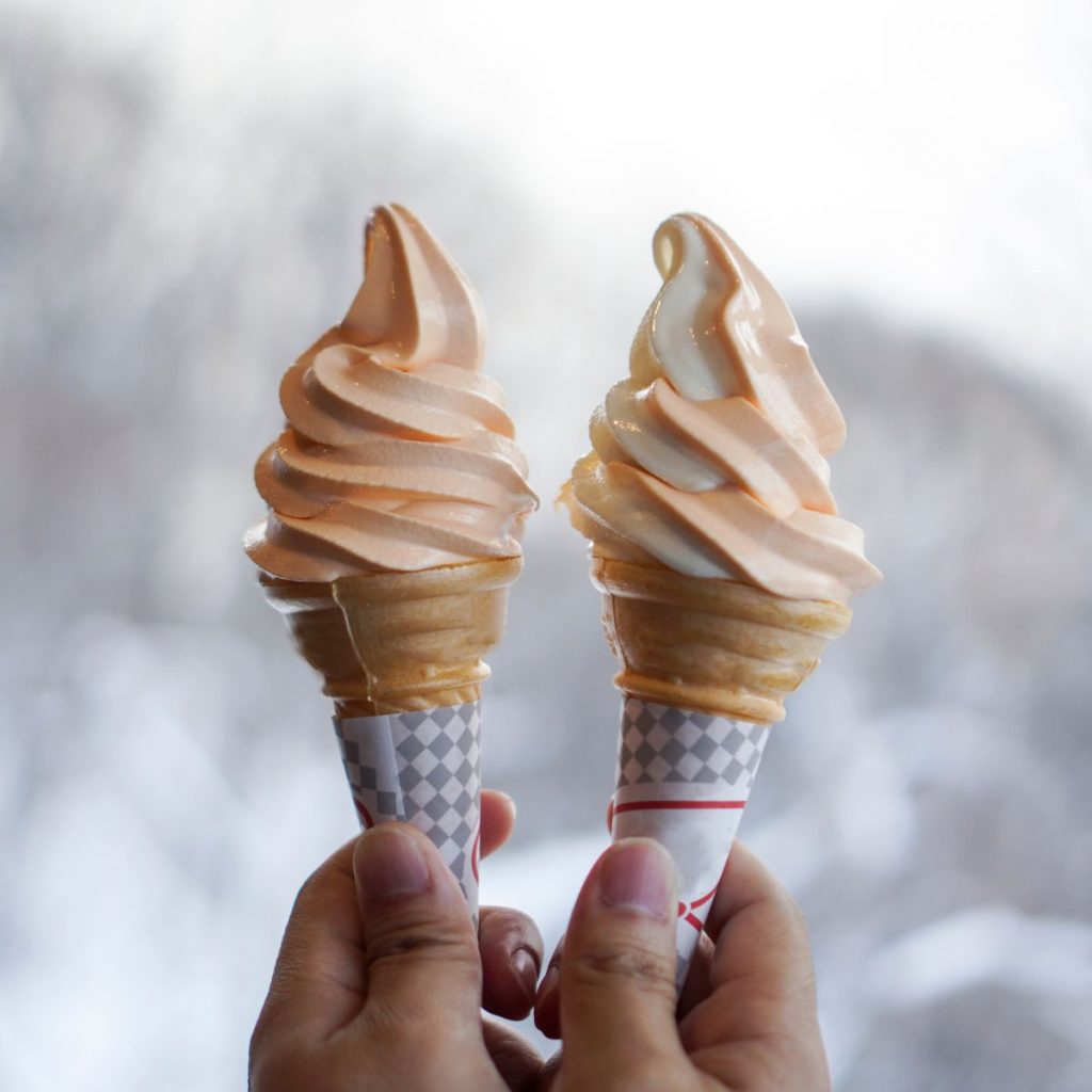 Two vanilla ice creams are held together for a close-up shot.