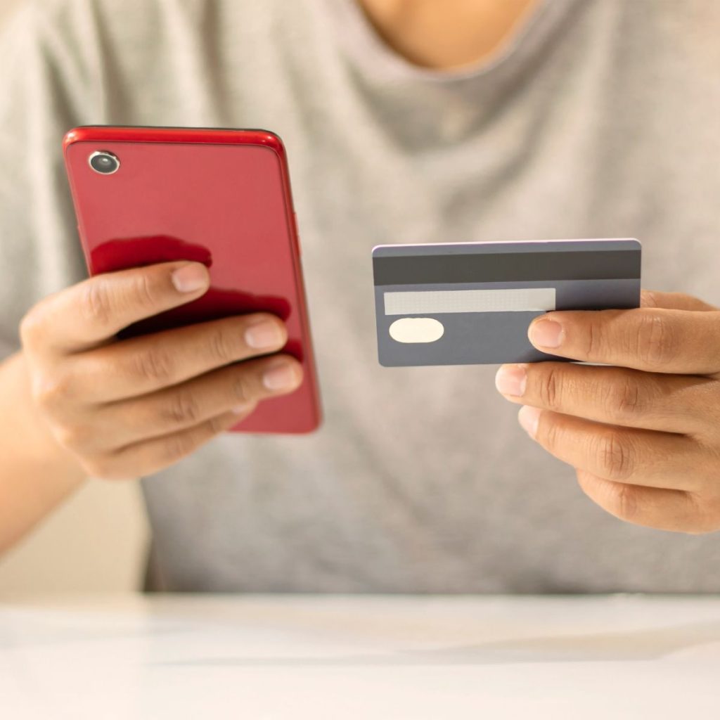 A man holds a cell phone and a credit card together.