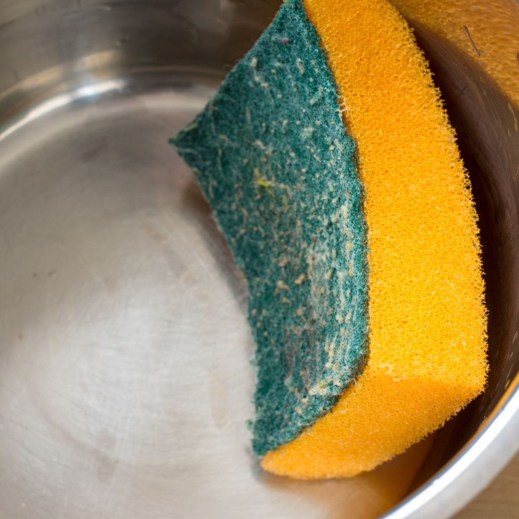 A sponge rests inside a stainless steel pan.