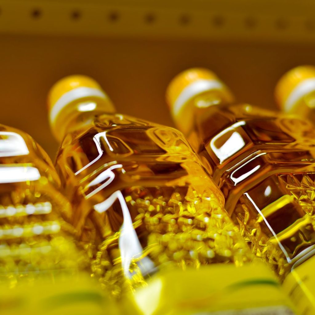 Bottles of vegetable oil rest on a supermarket rack.