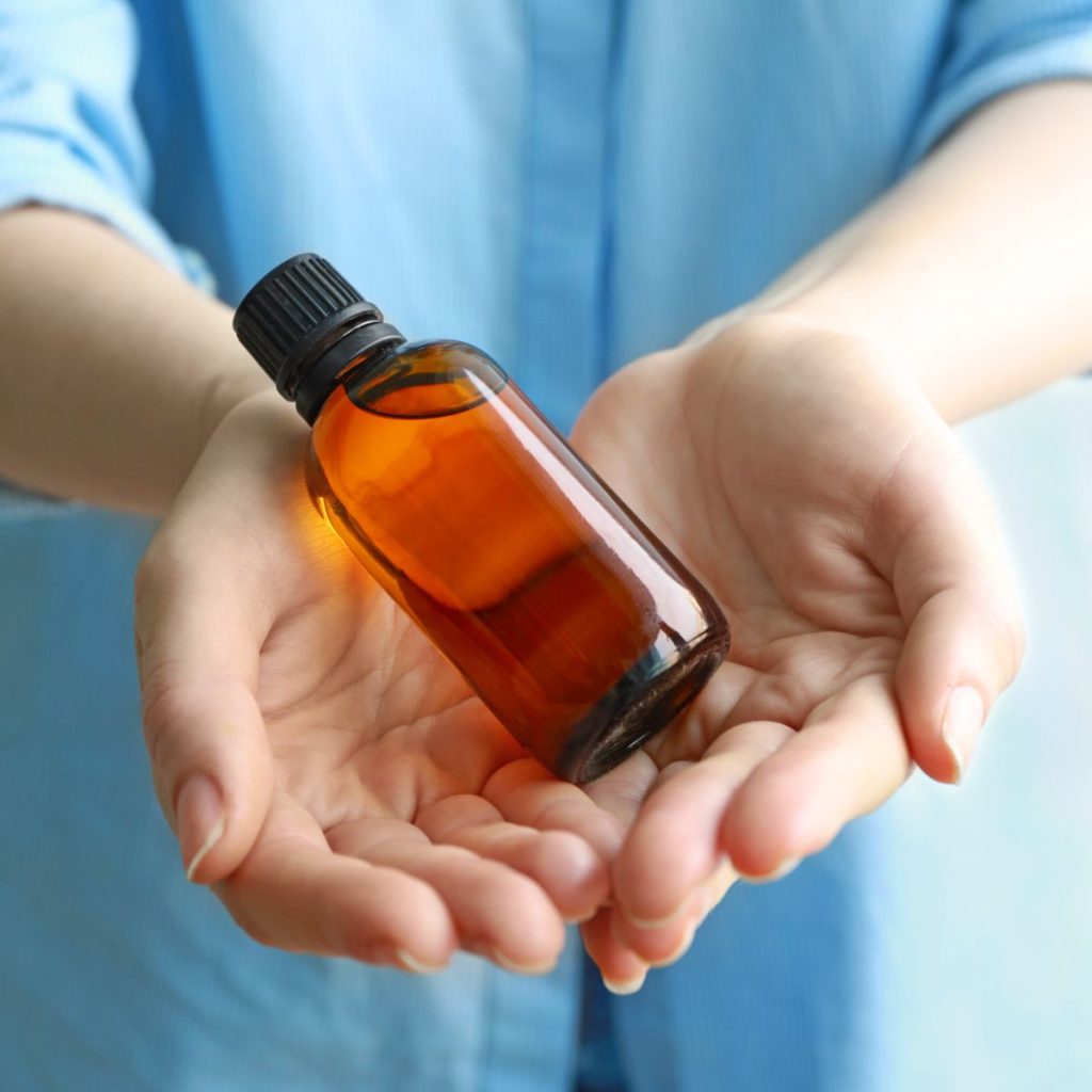 A bottle of vanilla extract rests on a human's palms.